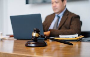A gavel next to a man browsing his laptop, symbolizing digital access to family lawyers and legal services.
